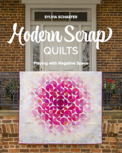 A book cover featuring a pink and white quilt draped over a railing. The title is "Modern Scrap Quilts: Playing with Negative Space" by Sylvia Schaefer